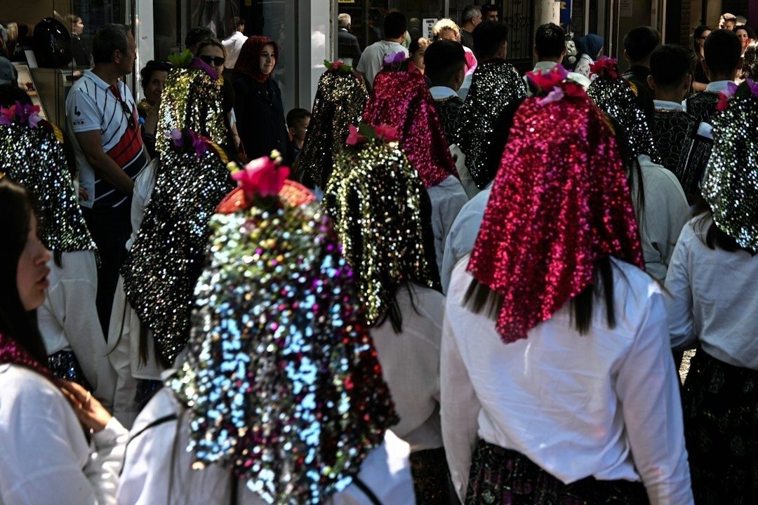 Menschen in weißen Festhemden mit glitzernden, blumengeschmückten Kopfbedeckungen