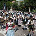 Blaskapelle und Trachtenträger ziehen bei einem Volksfest durch die Straße