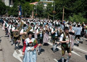Blaskapelle und Trachtenträger ziehen bei einem Volksfest durch die Straße