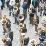 Blaskapelle mit zahlreichen Blechbläsern auf einem belebten Festplatz